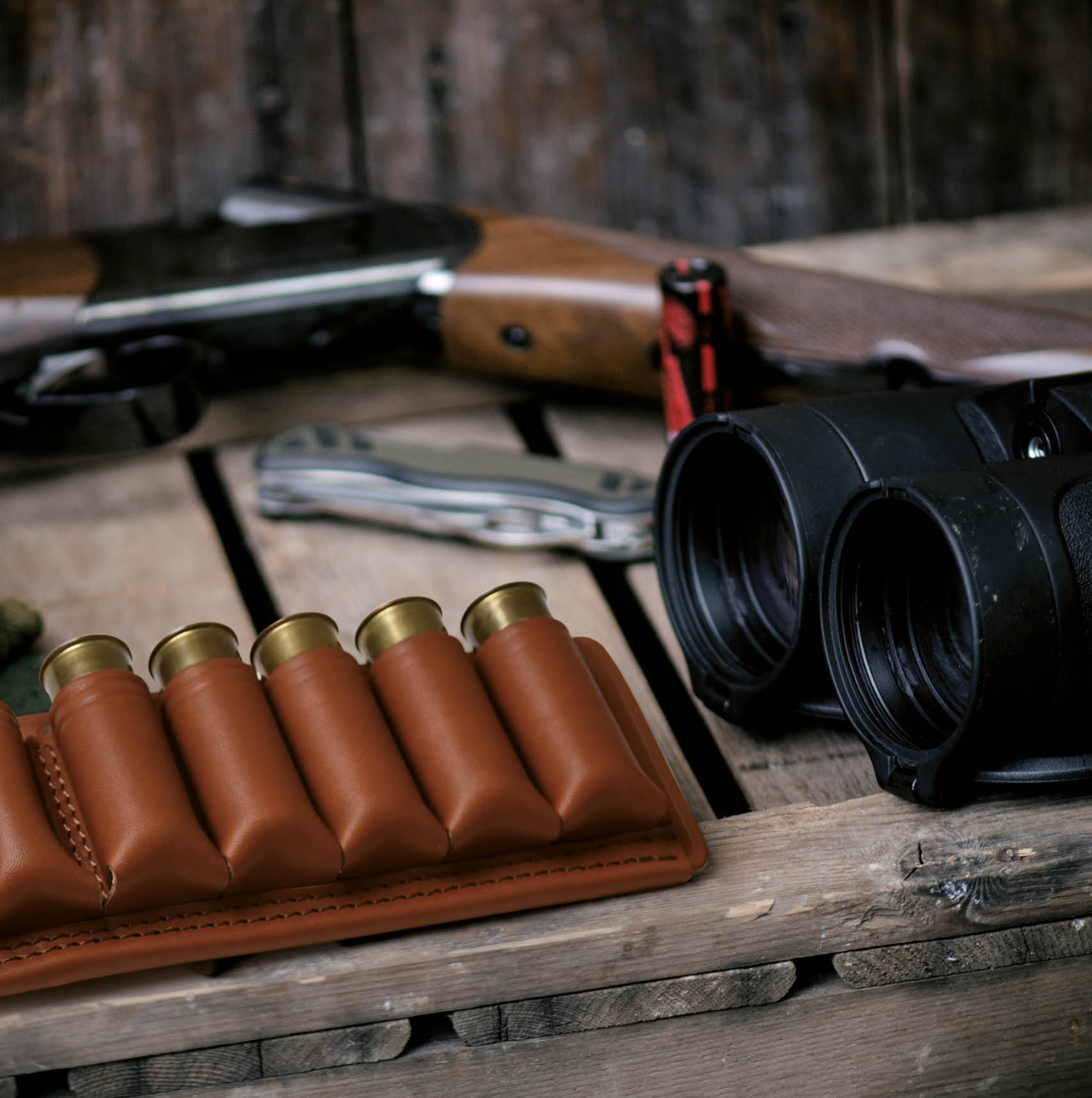 Professional hunters equipment for hunting. Detail on the ammunition. Wooden black background with rifle, hat, and other equipment for hunting.